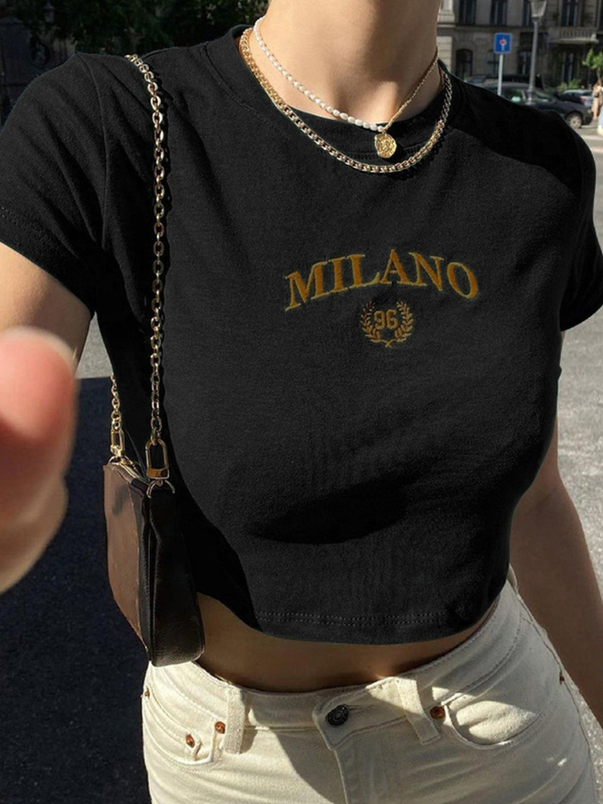 A Classy Chic Boutique black crop top with gold Milano 96 embroidery, styled with a gold chain necklace.